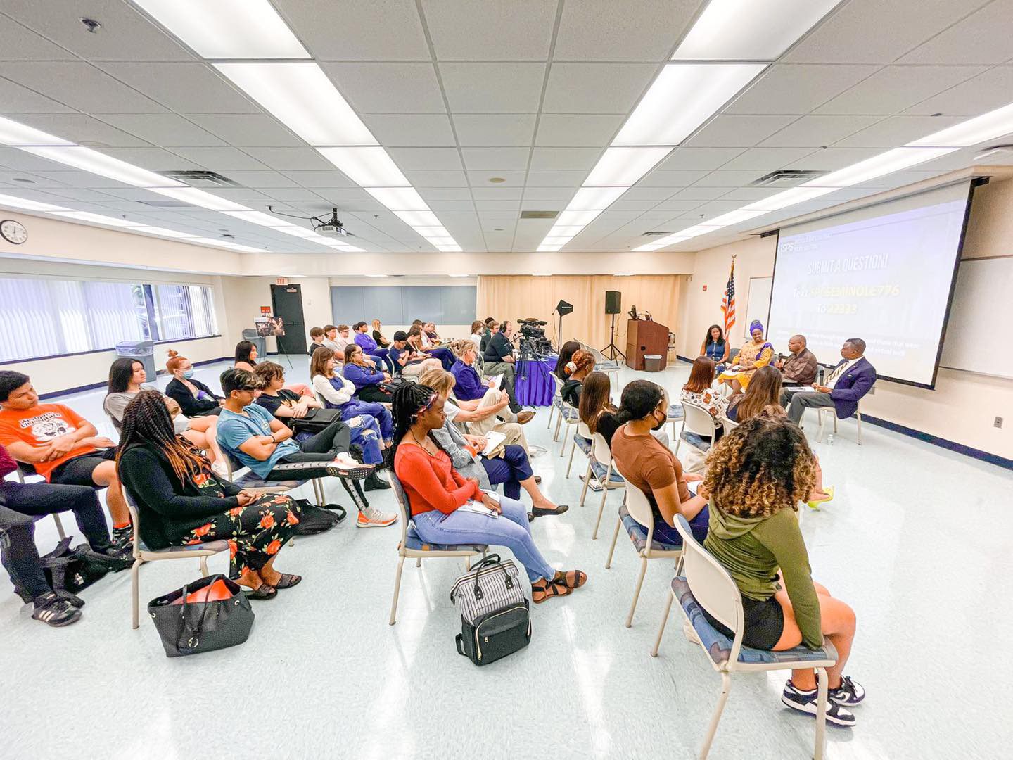 A group of students sitting in a conference and listening to guest speakers