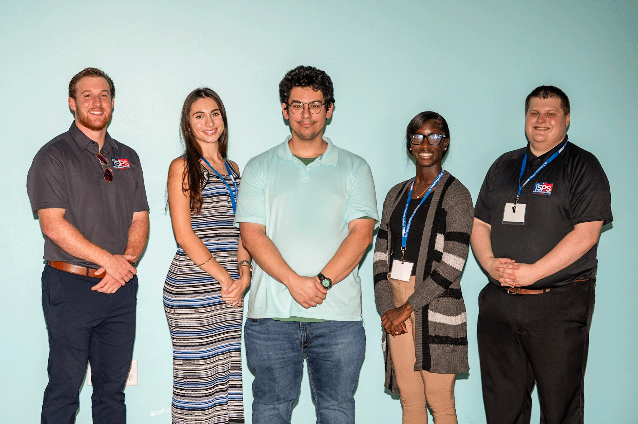 A group of ISPS student fellows standing in line for a group photo in front of a light-blue background.