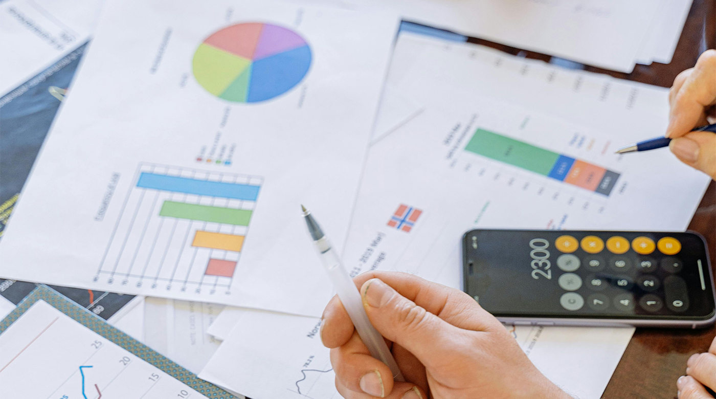 An assortment of papers with charts overwhelm space on a office desk.